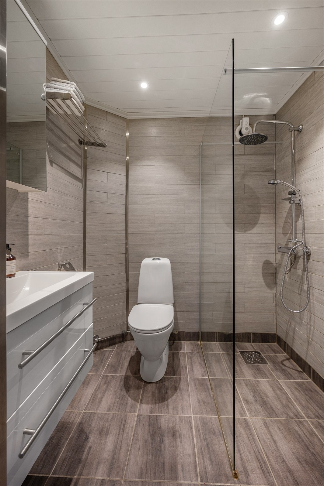 Tiltalende bad fra 2015 bestående av flislagte gulv med elektriske varmekabler, flislagte vegger og malt himling. Badet er innredet med dusjvegger, toalett og baderomsinnredning med servant. Galleribilde