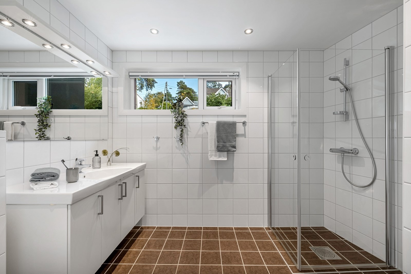 Stor bad/vaskerom med flis på gulv og vegger og tak i malte plater m/downlight Galleribilde