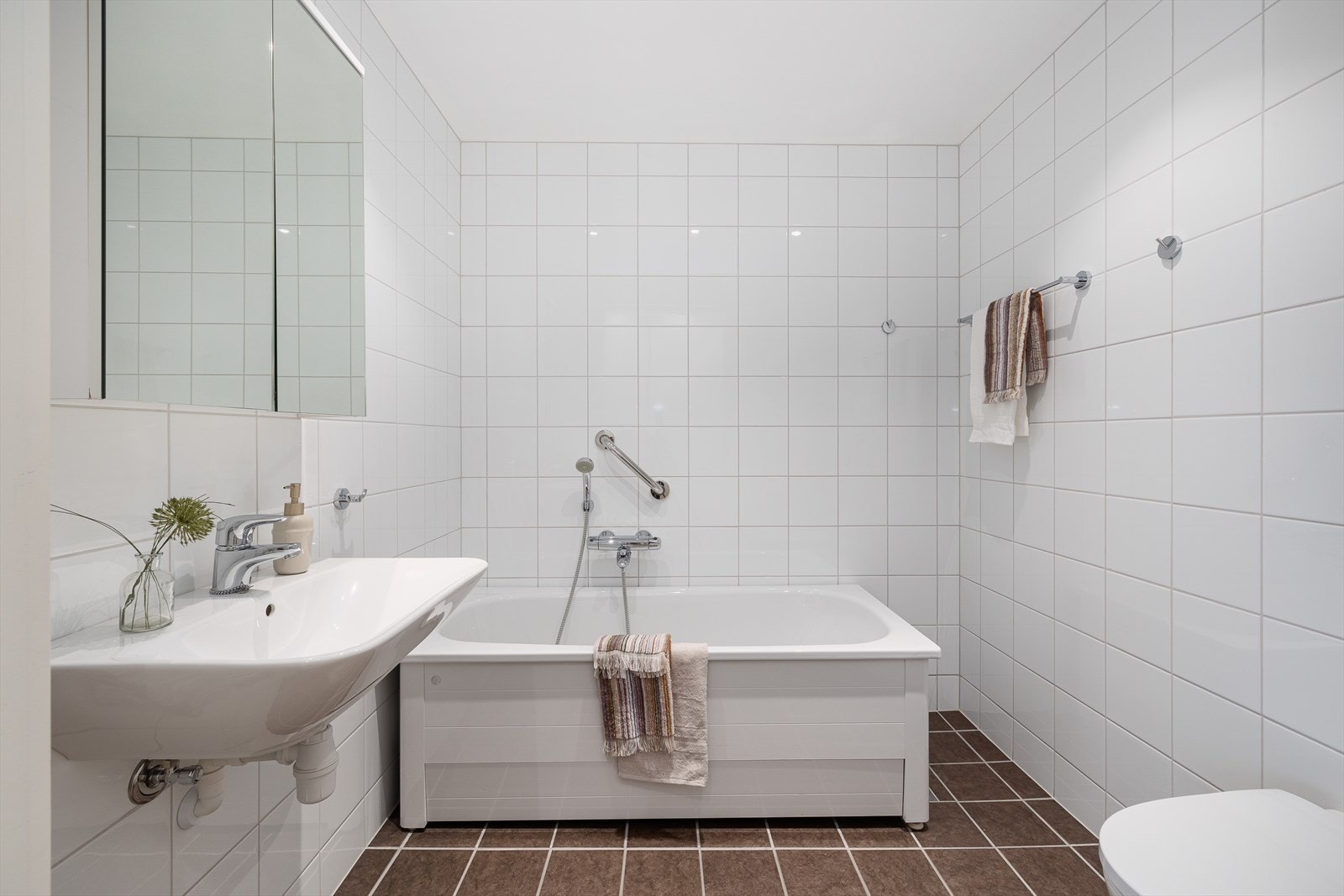 Innredet med badekar, servant, speilskap og vegghengt klosett Galleribilde