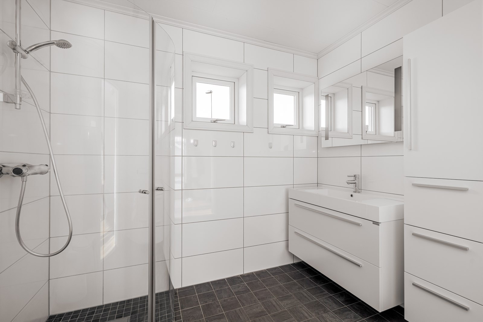 Lyst og pent, flislagt bad av god størrelse. Badet er utstyrt med varmekabler i gulv, toalett og dusjhjørne, samt opplegg for vaskemaskin. Galleribilde