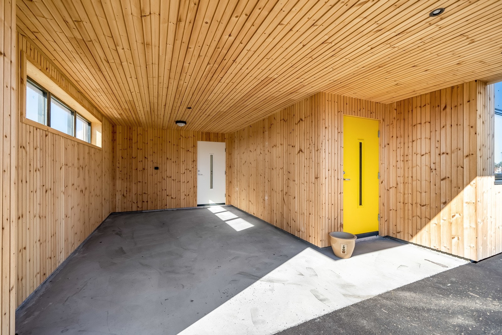 Carport med overbygd inngangsparti. Inngang til bolig og bi-inngang som fører inn i vaskerom. Galleribilde