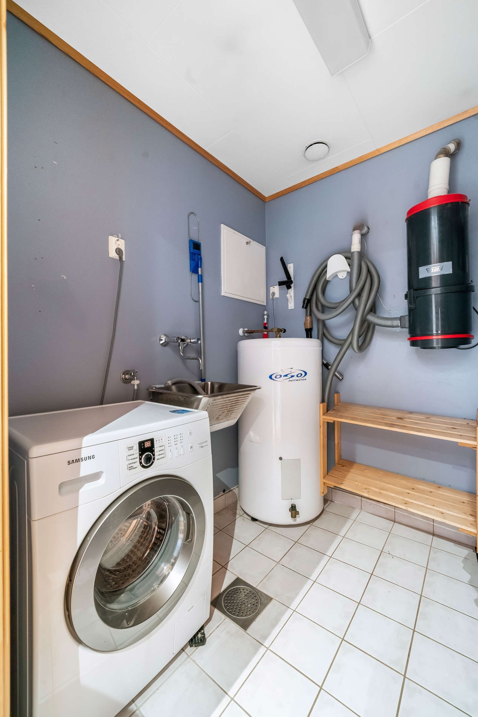 Gulvflate med fliser og varme. Vegger med malte flater, samt himling med folierte takplater. Utstyrt med vegghengt utslagsvask med to-greps armatur. Kran for tilkobling av vaskemaskin. Varmtvannsbereder og sentralstøvsuger. Galleribilde
