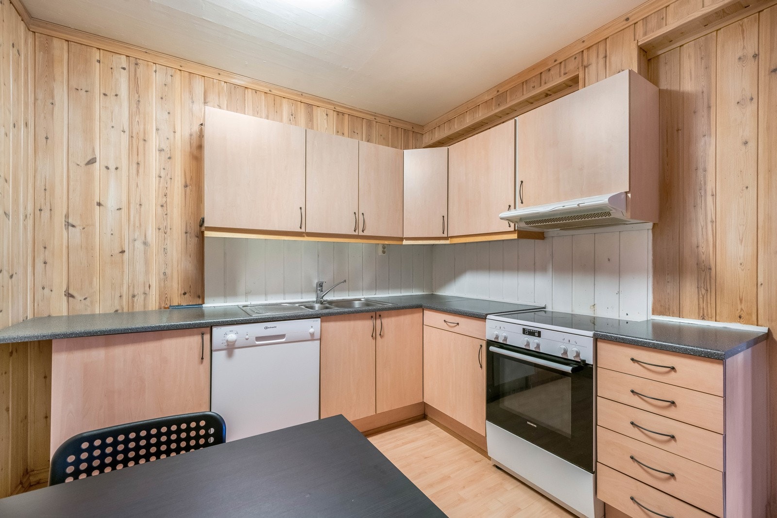 Kjøkkeninnredning fra byggeår med slette fronter. Benkeplater av laminat og nedfelt oppvaskkum med ett-greps blandebatteri. Benkeskapsbelysning og stikkontakter under overskap. Nisje til komfyr og oppvaskmaskin i benk. Ventilator under overskap. Galleribilde