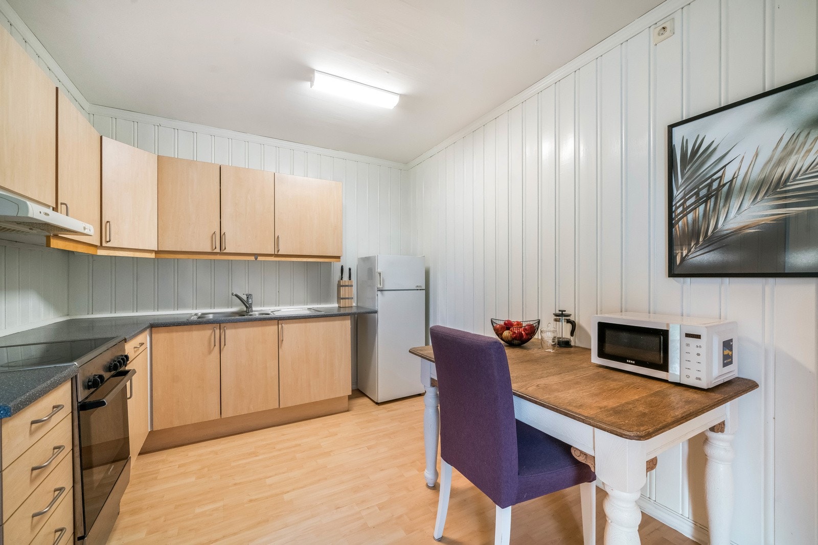 Kjøkkeninnredning fra byggeår med slette fronter. Benkeplater av laminat og nedfelt oppvaskkum med ett-greps blandebatteri. Benkeskapsbelysning og stikkontakter under overskap. Nisje til komfyr og oppvaskmaskin i benk. Ventilator under overskap. Galleribilde