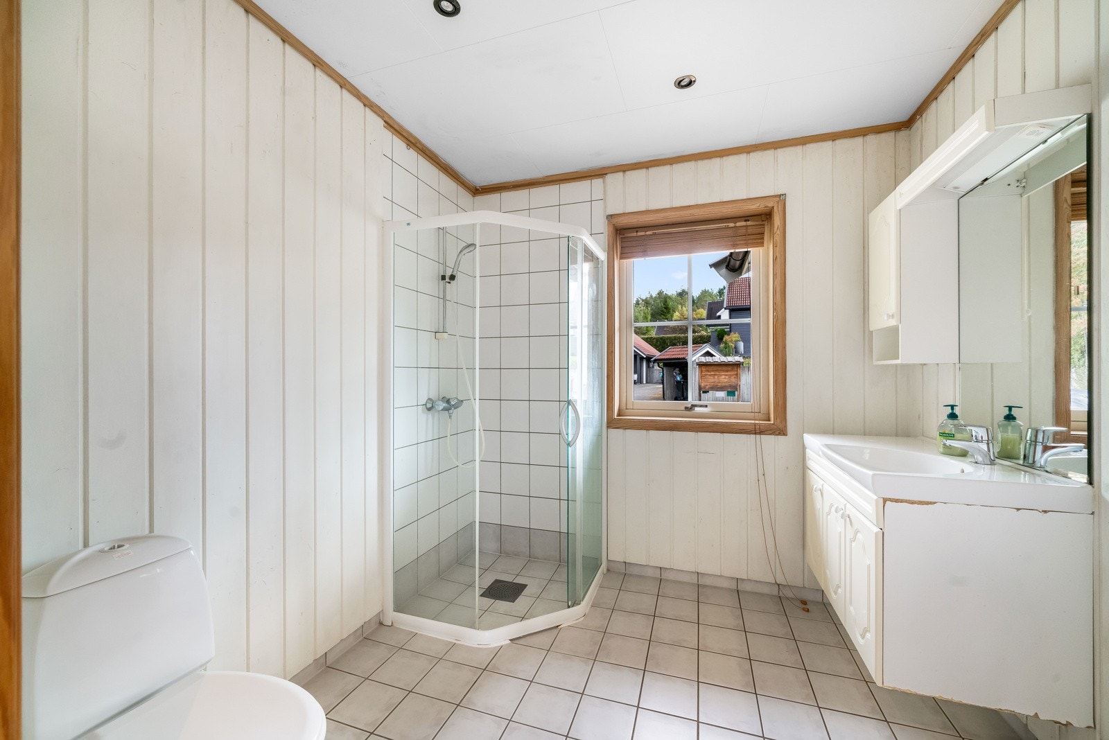 Flislagt gulv med varme, vegger med panel. Fliser på vegg i dusjsonen. Himling med folierte takplater og downlights. Baderommet er utstyrt med vegghengt servantskap, dusj og toalett. Galleribilde