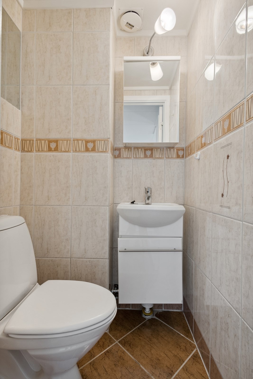 Separat flislagt wc-rom utstyrt med gulvstående wc og servantinnredning med under- og overskap. Galleribilde