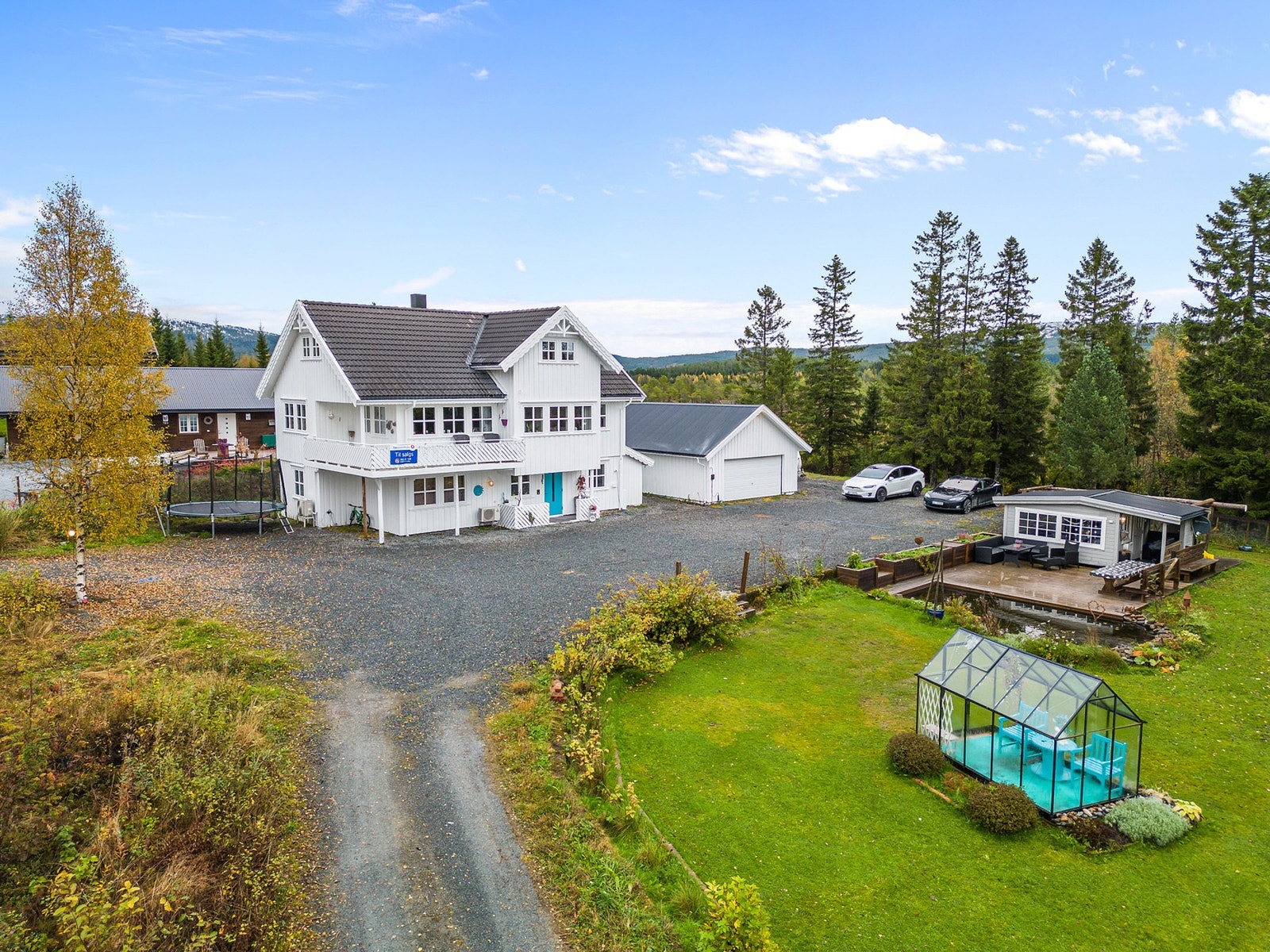 Innholdsrik eiendom med hus i tre etasjer, stor garasje, hagestue og drivhus. Galleribilde