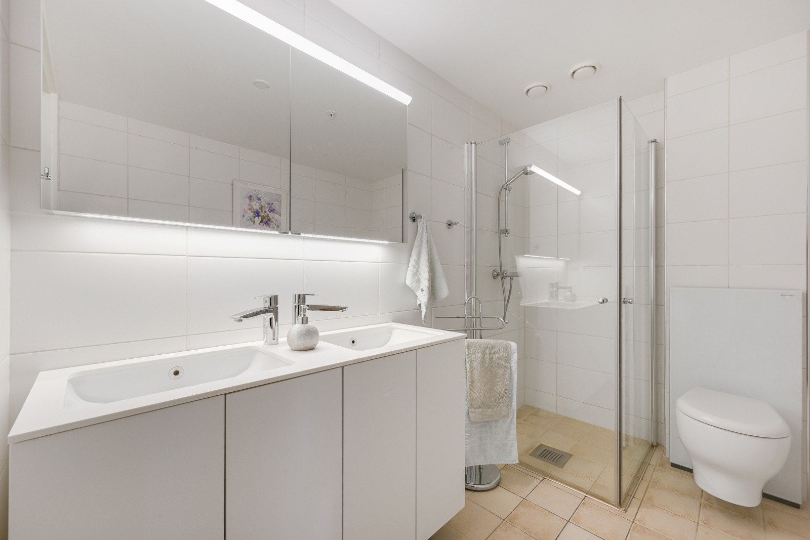 Badet er innredet med praktiske dusjvegger, pen baderomsinnredning og vegghengt klosett. Galleribilde