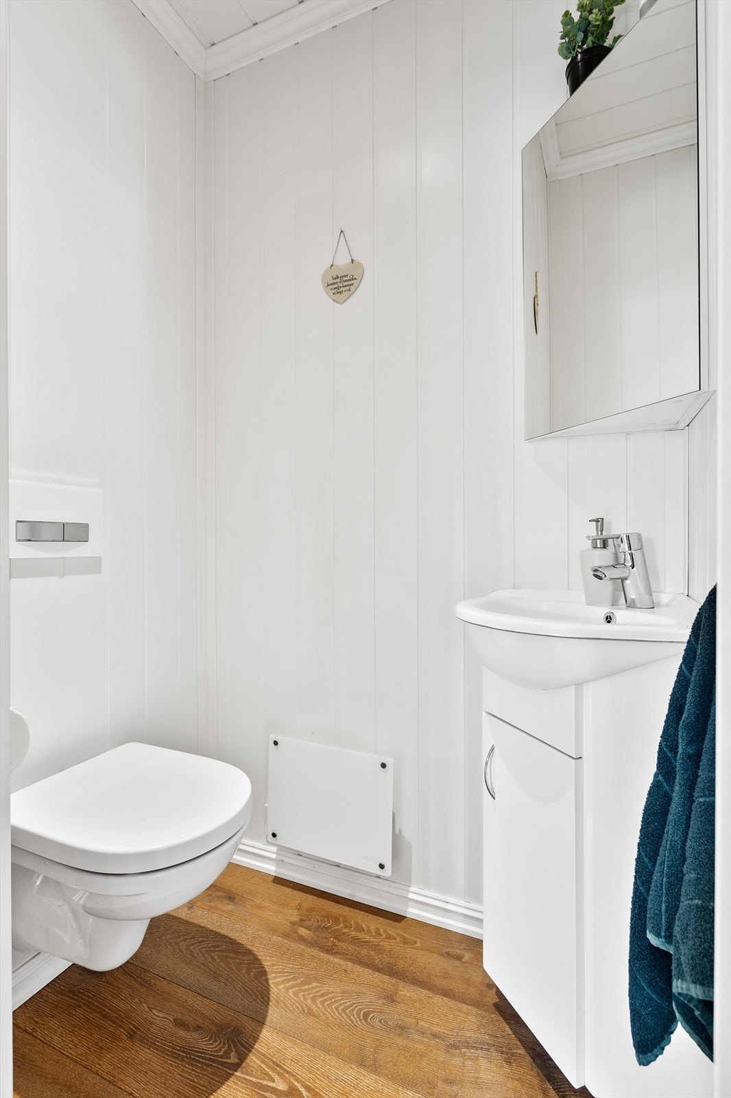 Det er laminat på gulvet og panelplater på veggene. Rommet er utstyrt med vegghengt wc og servantinnredning med under- og overskap. Galleribilde