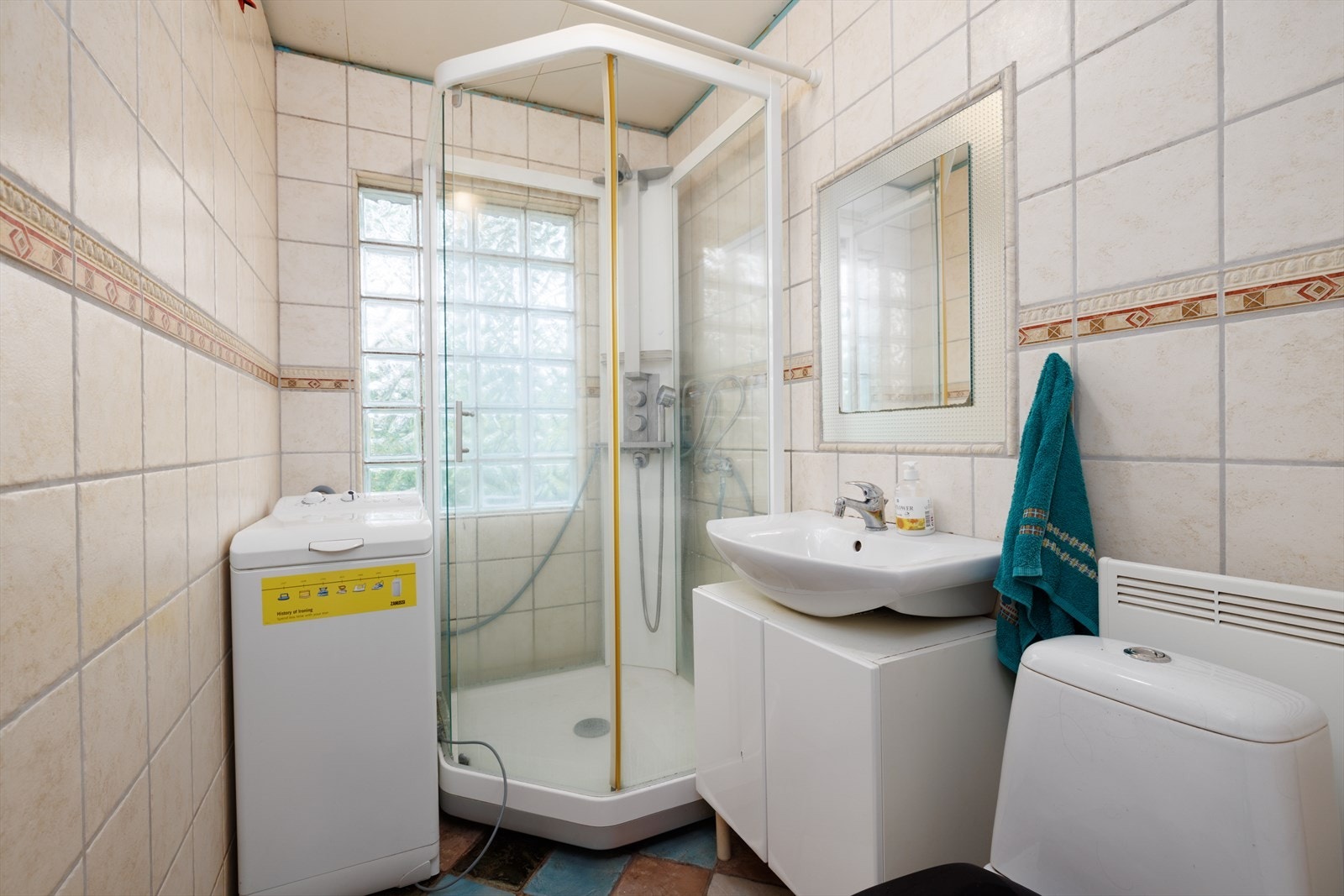 Badet er innredet med dusjkabinett, servant på innredning og toalett. Galleribilde