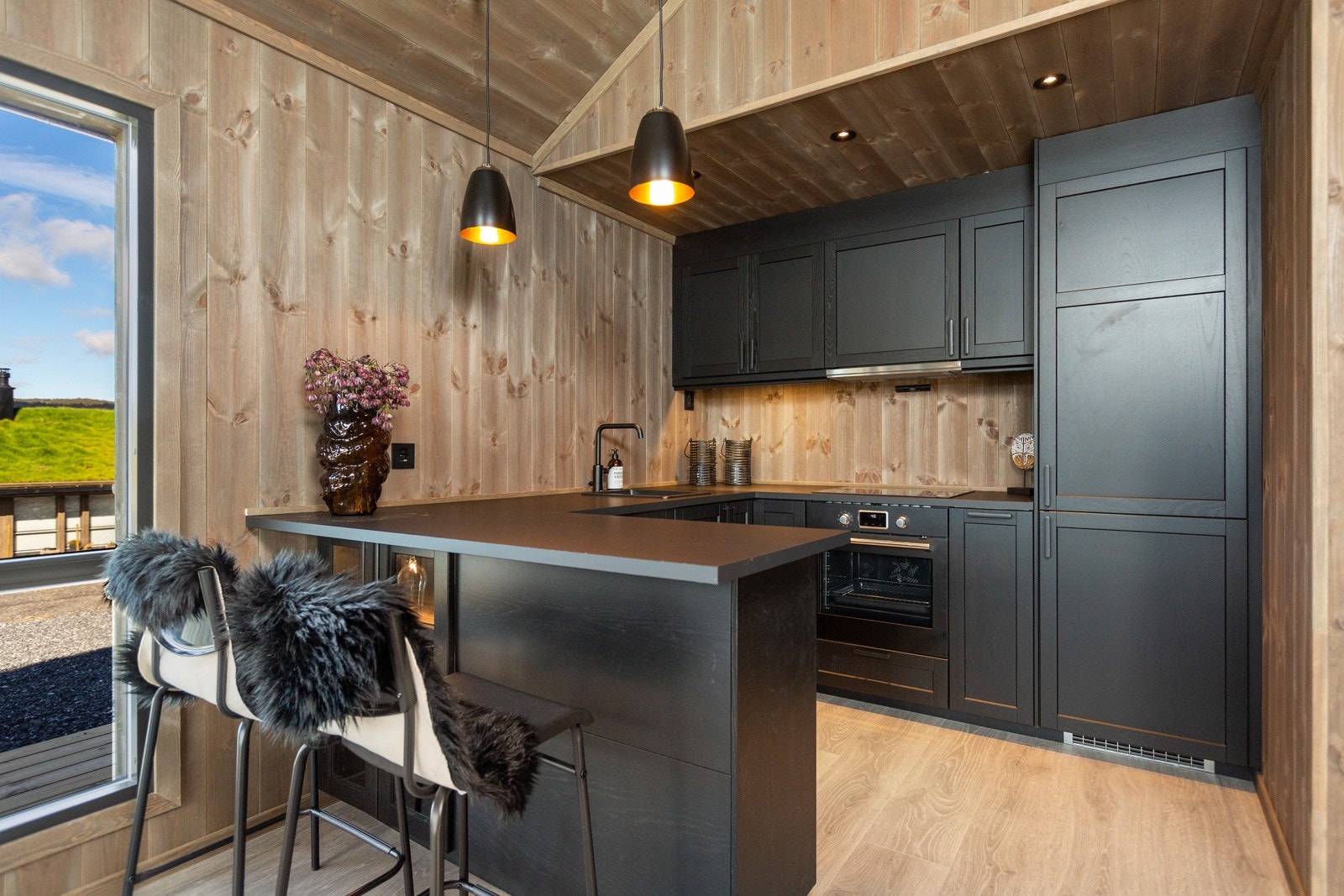 En flott halvøy gir et praktisk skille mellom stue og kjøkken, samt ytterligere skap og benkeplass Galleribilde