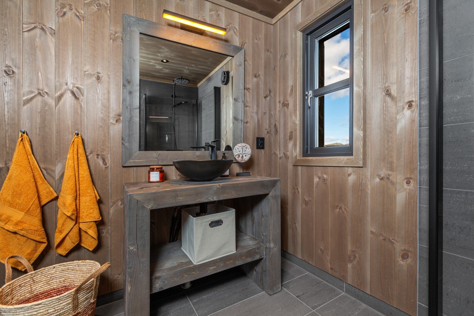 Badet er innredet med pent, håndlaget baderomsmøbel med servant og vegghengt speil Galleribilde