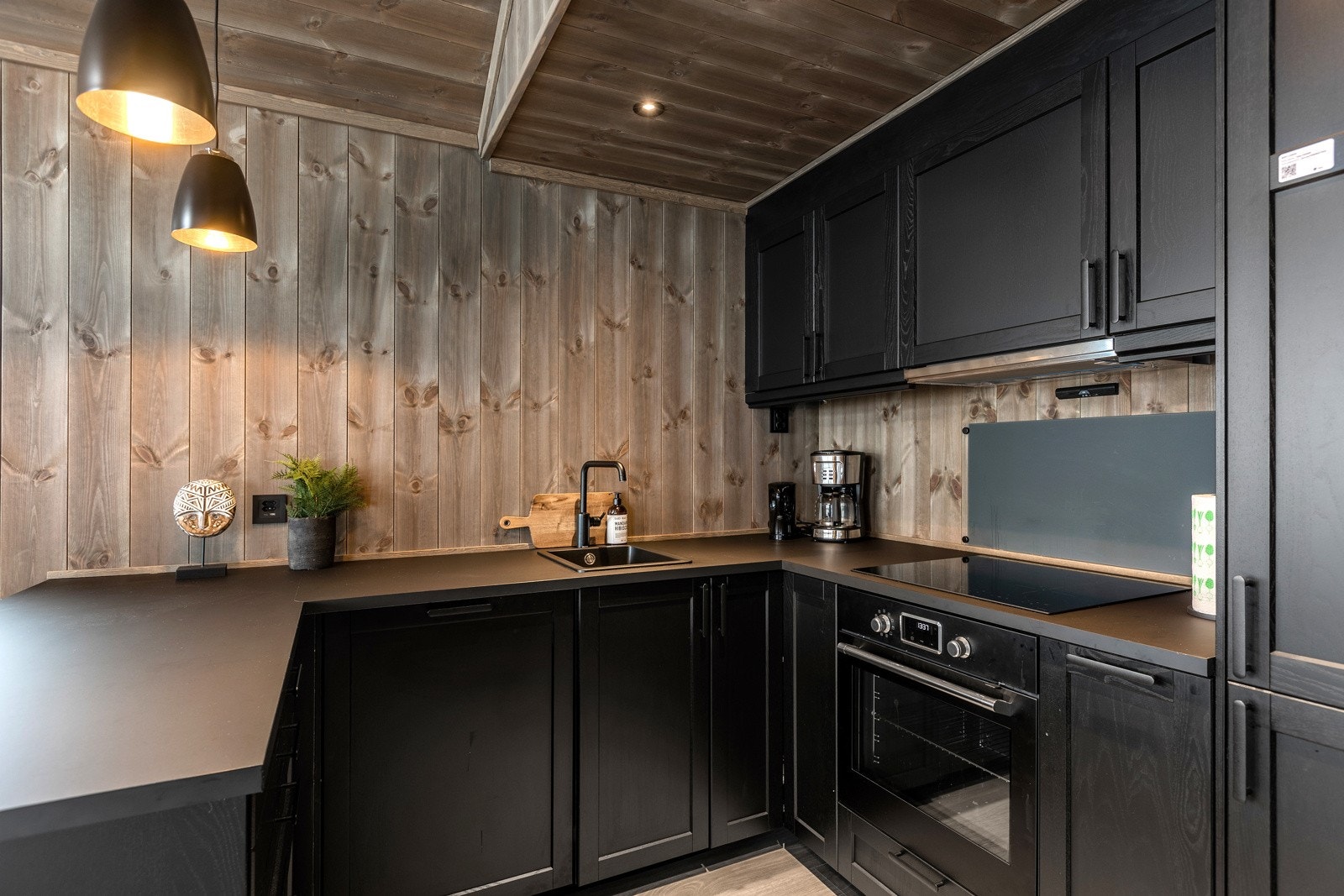 Elegant kjøkken med velutstyrt og påkostet innredning med mørke, profilerte fronter Galleribilde