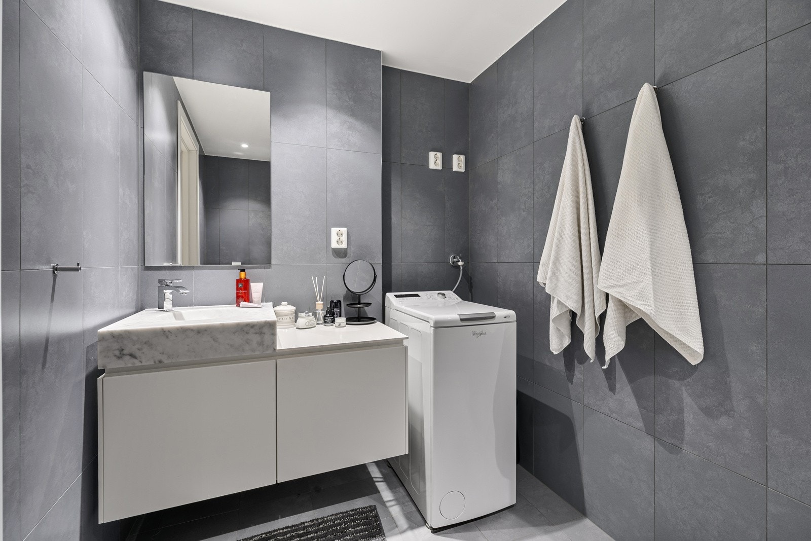 Badet inneholder blant annet servantskap med speil på vegg over servant og vegghengt klosett. Galleribilde
