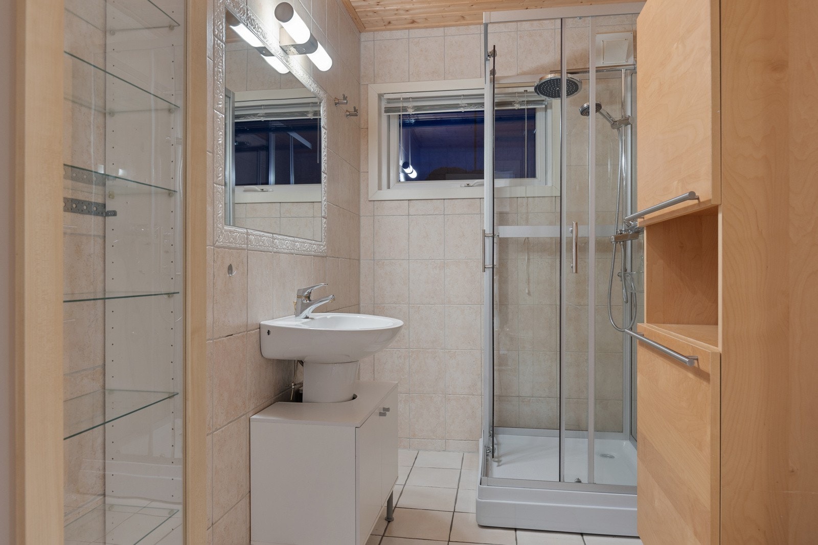Bad i 1. etasjen med flislagt gulv med gulvvarme, flislagte vegger og dusjkabinett med dusjarmatur. Galleribilde