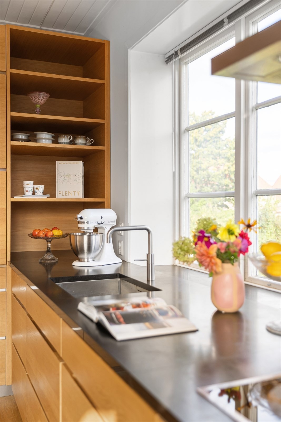 Det er rikelig med skap- og benkeplass til matlagingen. Fra kjøkkenvinduet er det frodig utsyn til nabolaget. Galleribilde