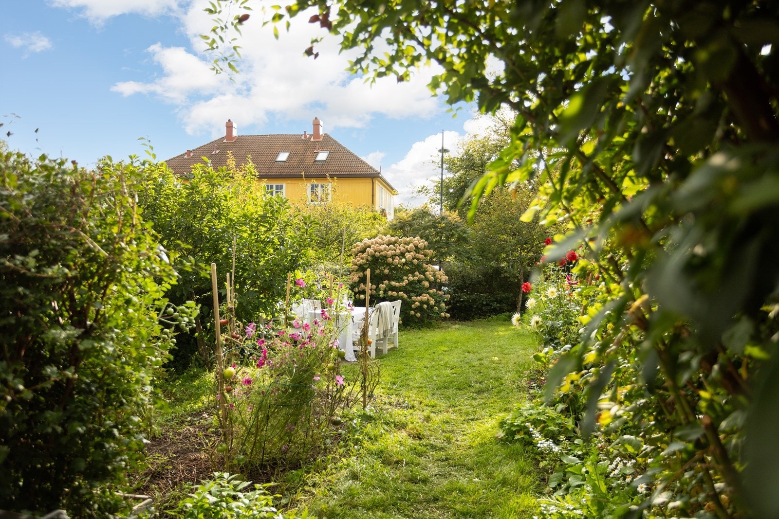 Hageparsellen utgjør en skjermet oase omkranset av grønn og frodig beplantning. Galleribilde