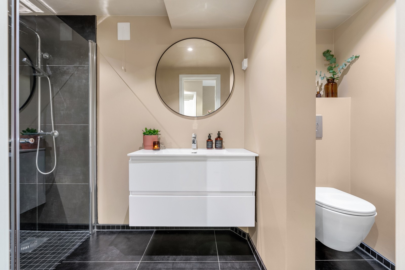 Videre inn til boligens flotte baderom som også er pusset opp i 2019! Flisvalget er moderne og pent med store sortgrå vegg- og gulvfliser samt mosaikk flisfelt i dusjsone og gulvlister. Galleribilde