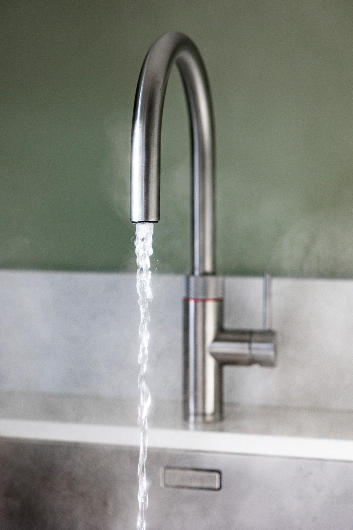 Kjøkkenet har en dekorativ underlimt servant i børstet stål med praktisk blandebatteri fra Quooker som gir kokende vann, rett i springen. Galleribilde