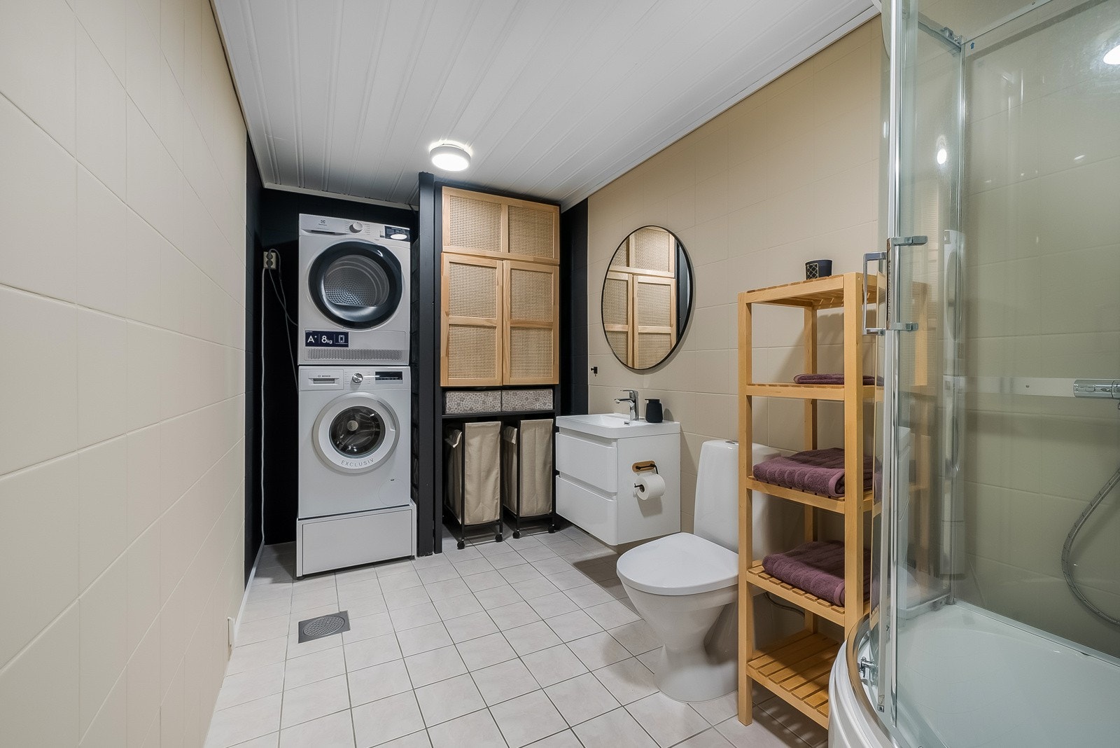 Pent bad med fliser på gulv og malte fliser på vegg. Badet er innredet med baderomsinnredning, toalett og dusjkabinett, samt en vaskeromsavdeling. Galleribilde