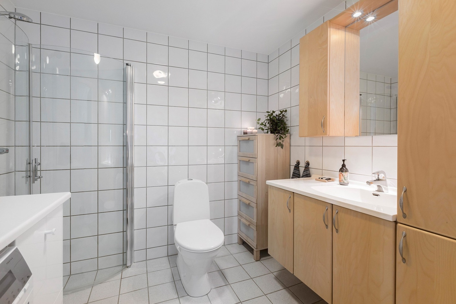 Pent flislagt baderom med behagelig varme i gulv. Rikelig med oppbevaringsplass, dusjhjørne med innfellbare glassvegger, opplegg for vaskemaskin med benkeplate over. Galleribilde