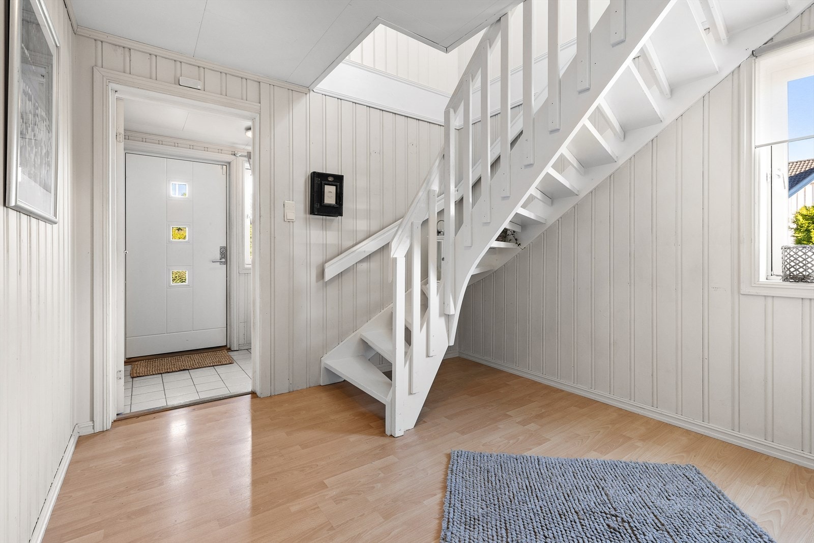 Entréen har flislagt gulv med varmekabler og skyvedørsgarderobe. Videre inn er det en romlig trappegang med plass til entrémøbler Galleribilde