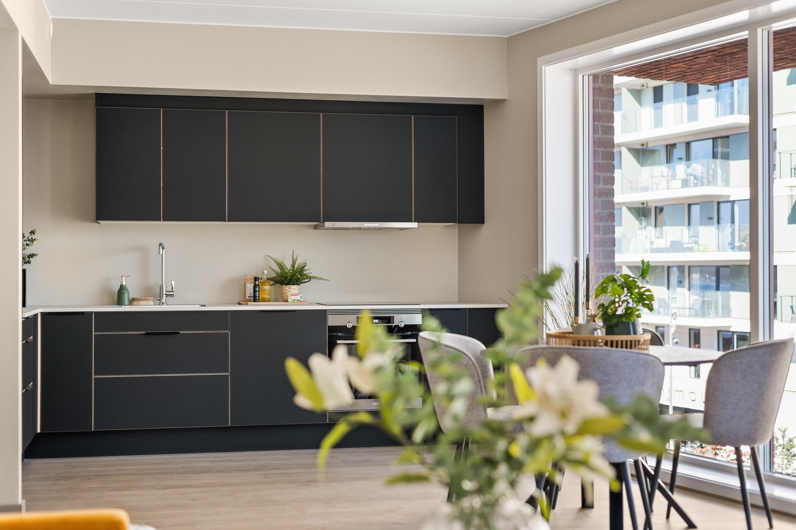 Lekker og moderne kjøkkeninnredning fra HTH med slette grå fronter og benkeplate med underlimt kum i rustfritt stål. Galleribilde