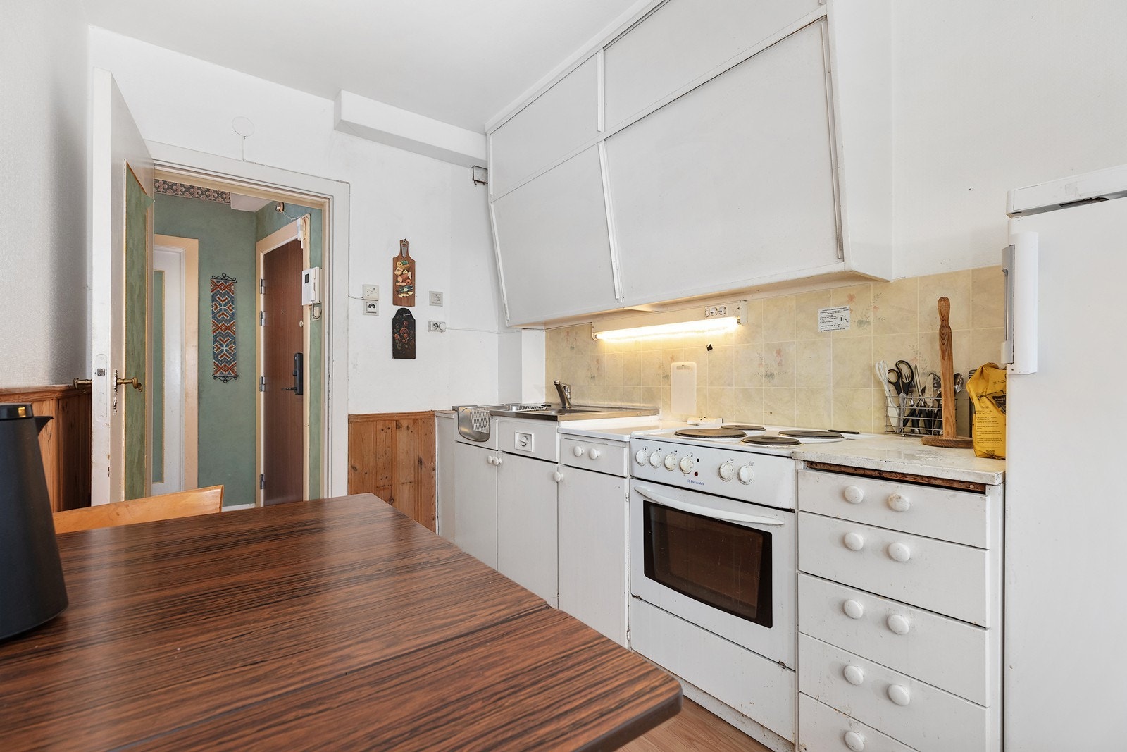 Hvitevarer består av frittstående komfyr og kjøleskap. Kjøkken uten ventilator. Galleribilde