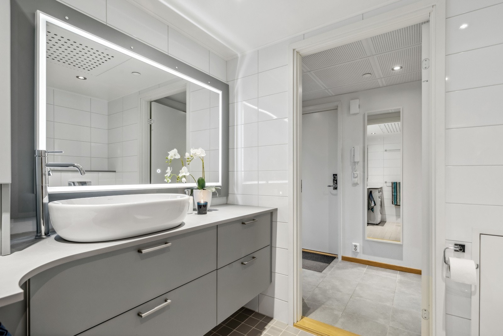 Nydelig flislagt bad med lekker baderomsinnredning. Her har du spotter i tak samt speil med integrert belysning. Galleribilde