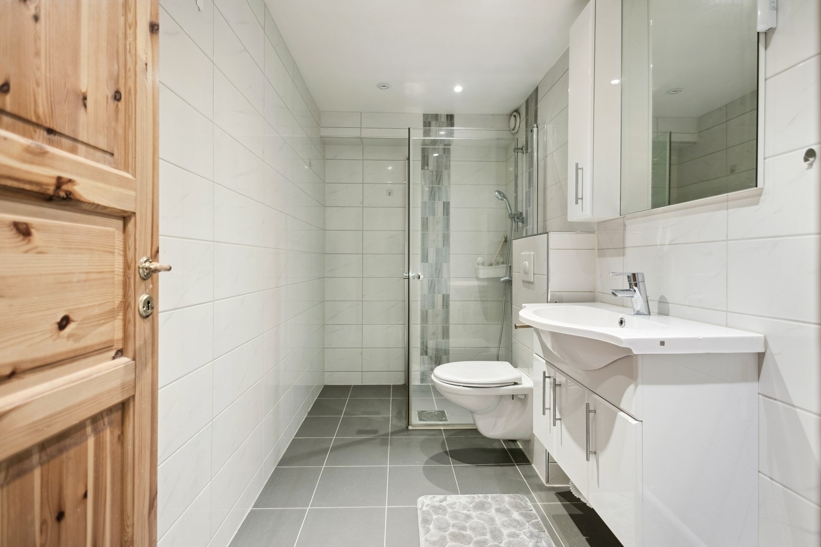 Badet ble pusset opp i 2014 og har innredning bestående av vegghengt wc, dusjsone med innsvingbare glassdører, samt servant med underskap, overskap, speil og belysning Galleribilde