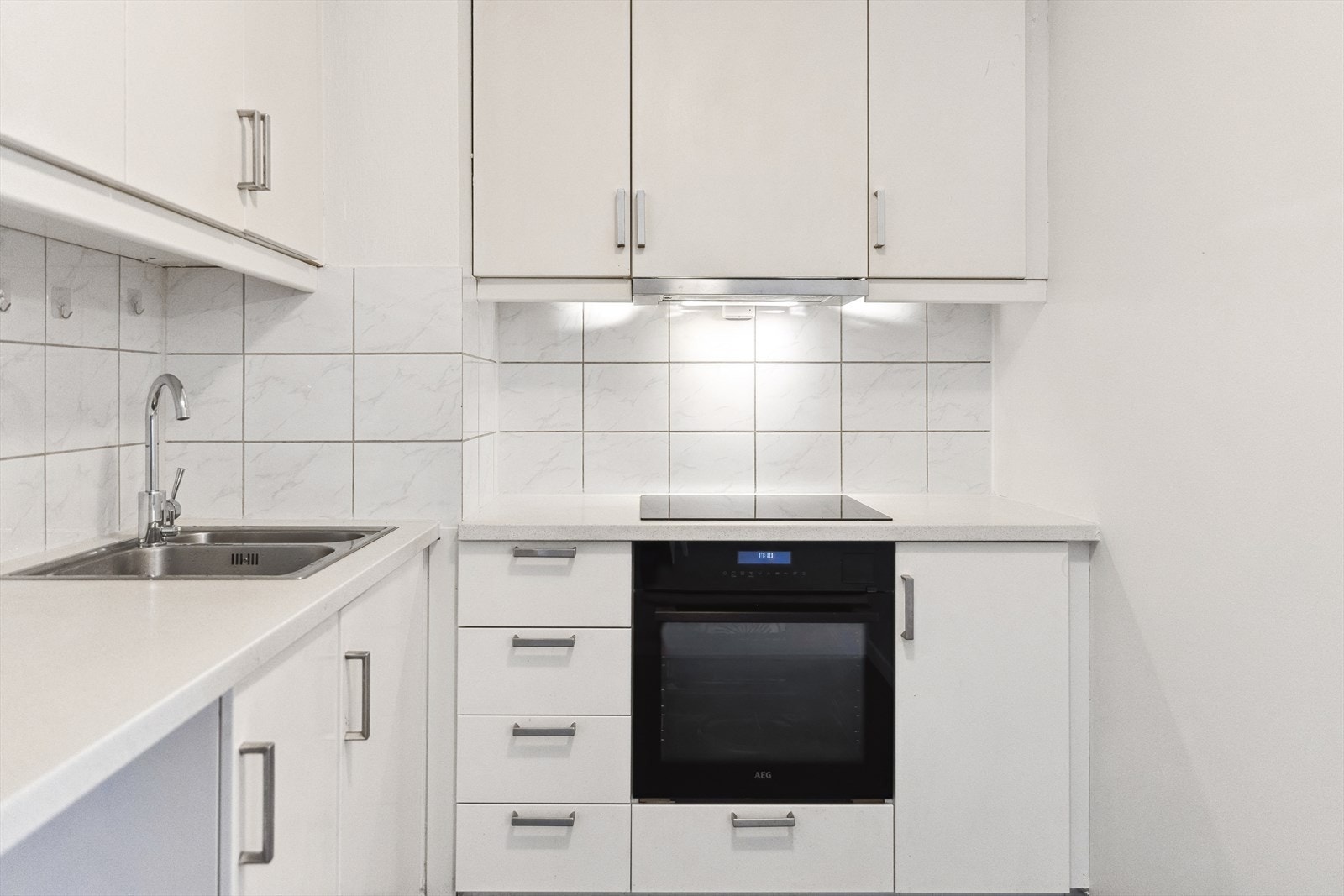 Hvit, glatt innredning fra Ikea med skuffer og skap. Benkeplater av laminat med fliser over Galleribilde