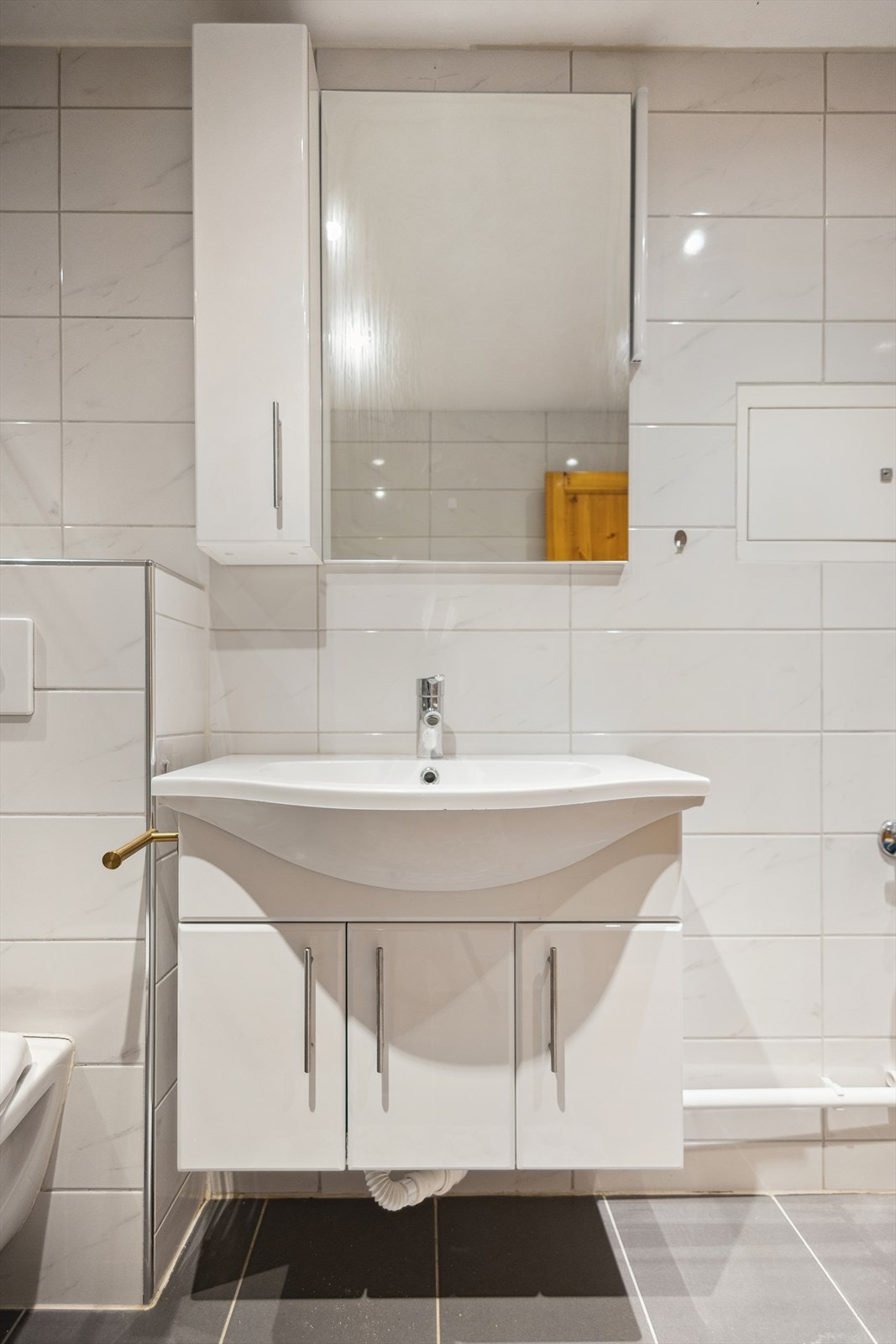 Badet ble pusset opp i 2014 og har innredning bestående av vegghengt wc, dusjsone med innsvingbare glassdører, samt servant med underskap, overskap, speil og belysning Galleribilde