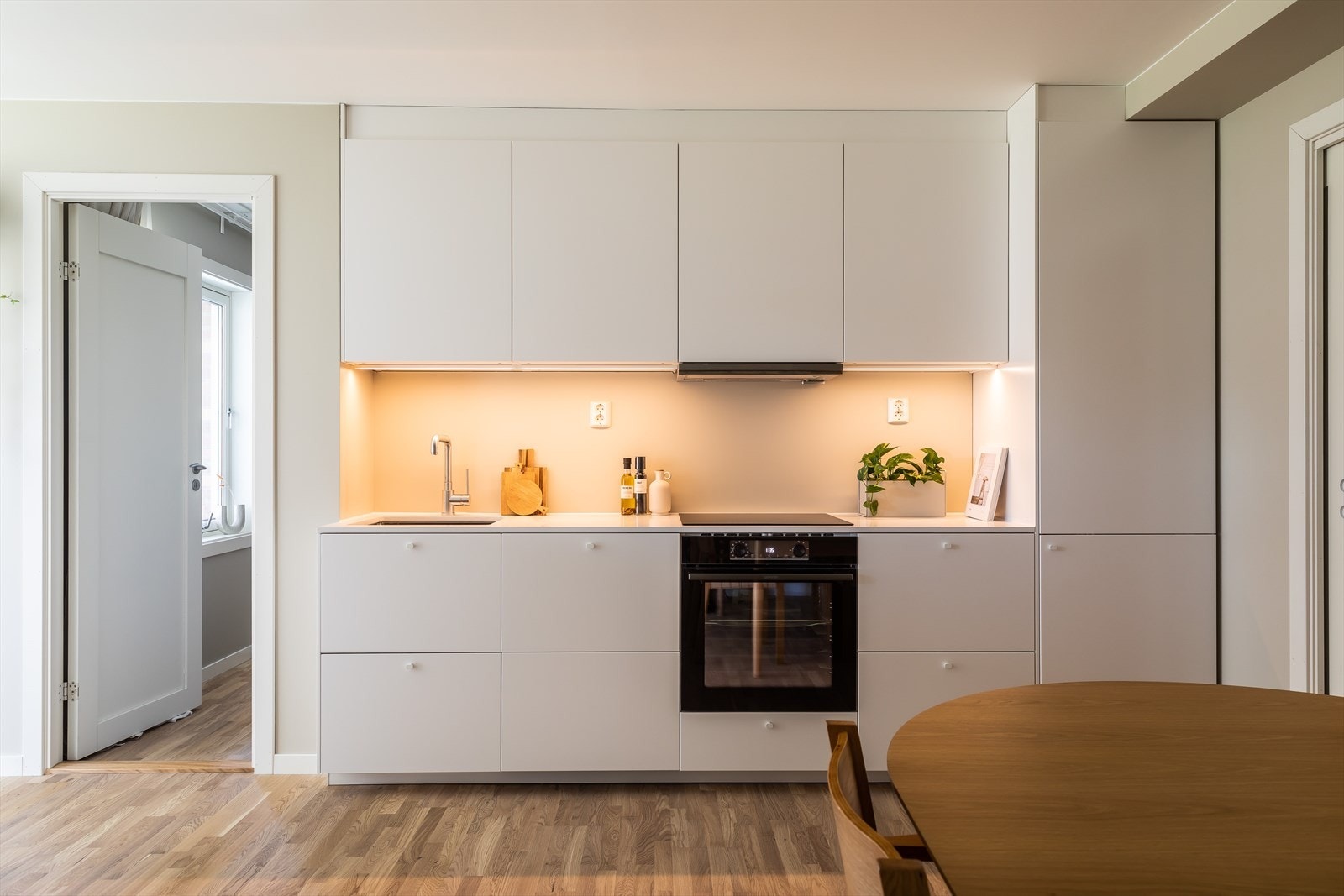 Lekker og påkostet IKEA-kjøkkeninnredning fra 2023 med malte fronter, stein benkeplate og integrerte hvitevarer som besstår av platetopp, stekeovn, oppvaskmaskin og kjøl- og frys Galleribilde