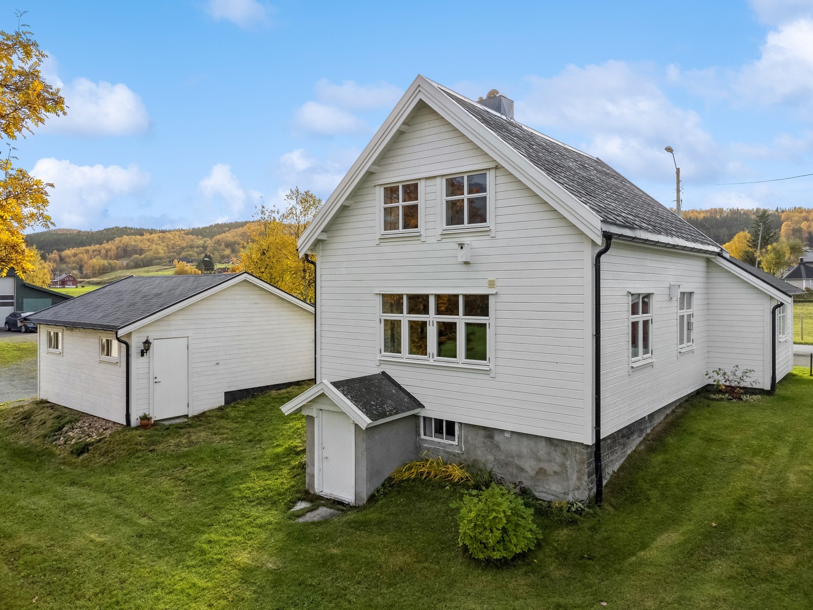 Pent opparbeidet ute rundt boligen med plen og beplanting. Galleribilde