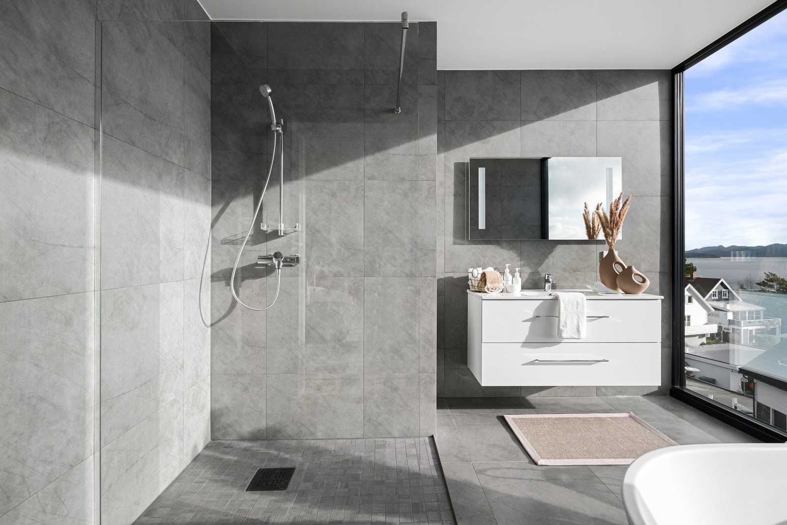 Baderommet er innredet med servantseksjon, speil med innfelt belysning, vegghengt toalett, badekar og dusjhjørne. Galleribilde