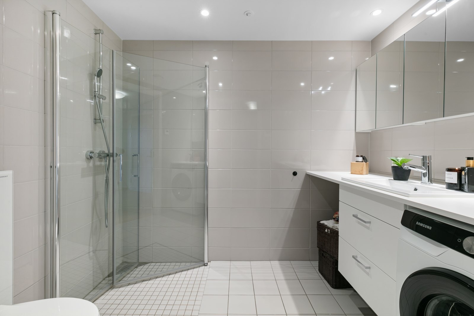 Badet har et delikat og tidløst uttrykk, og er innredet med lyse gulvfliser og beige flislagte veggoverflater. Det er behagelig gulvvarme Galleribilde