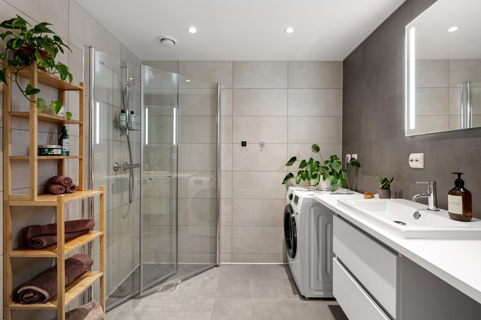 Moderne og delikat bad med store fliser i behagelige grå- og beige toner. Downlights i himling og varme i gulv. Galleribilde