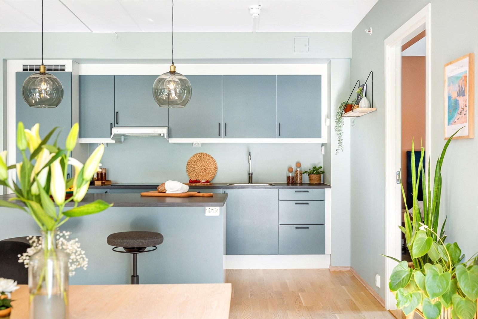 Kjøkkeninnredning bestående av lakkerte fronter, laminat benkeplate med nedfelt vaskekum og belysning over benkeplate. Galleribilde