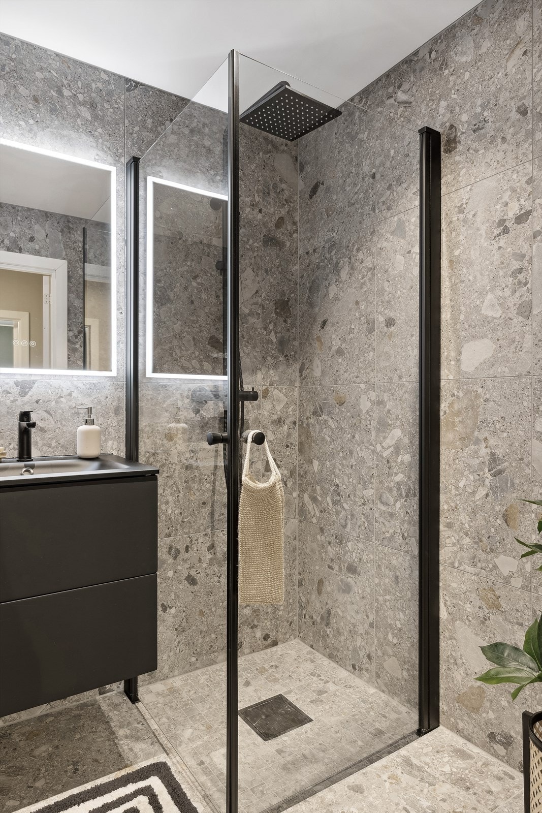 Smakfull innredning med matte, sorte detaljer og blant annet moderne, regnfallsdusj Galleribilde