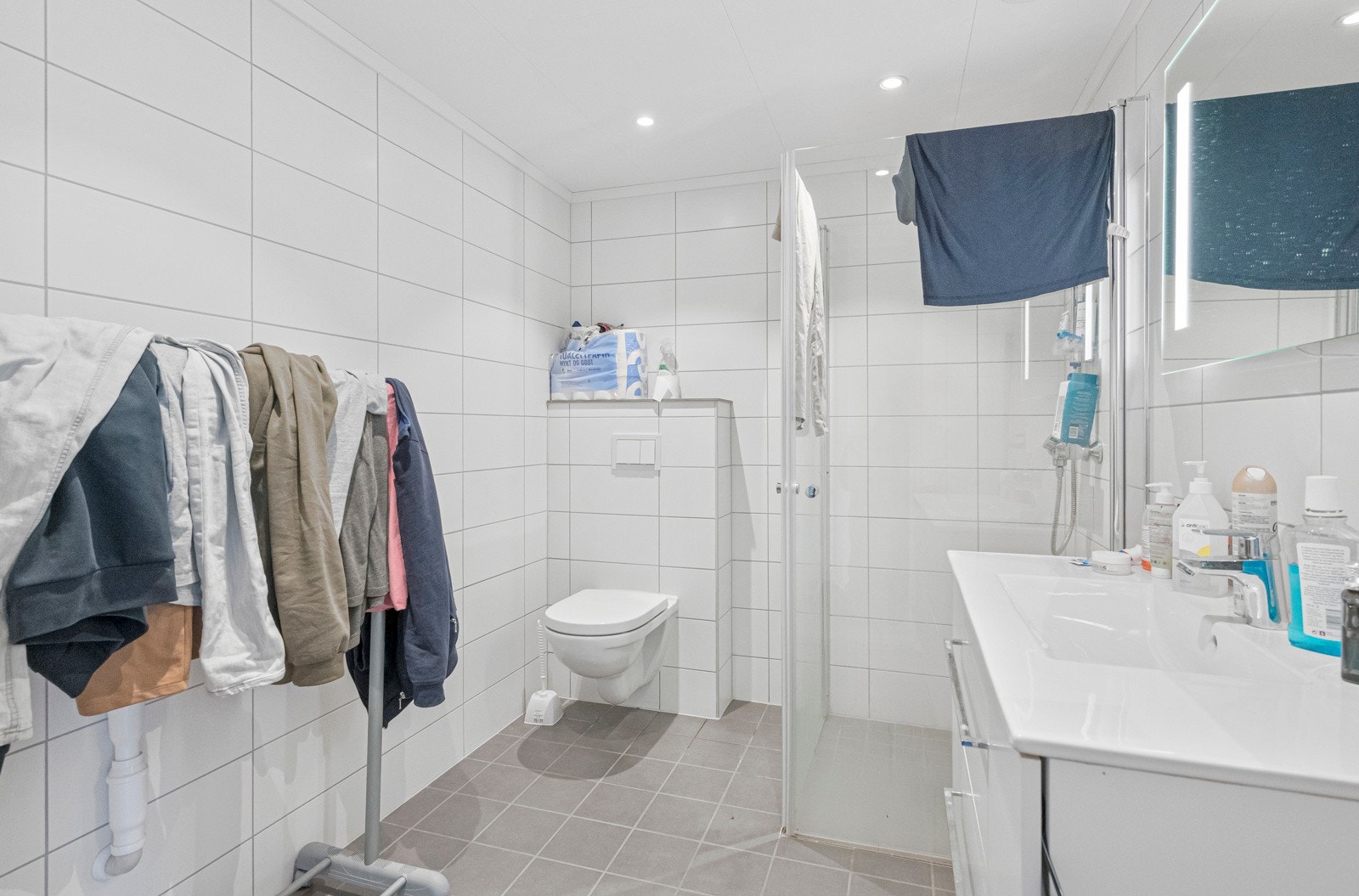 Badet er innredet med baderomsinnredning, duhjørne med dører, vegghengt toalett og opplegg for vaskemaskin. Galleribilde