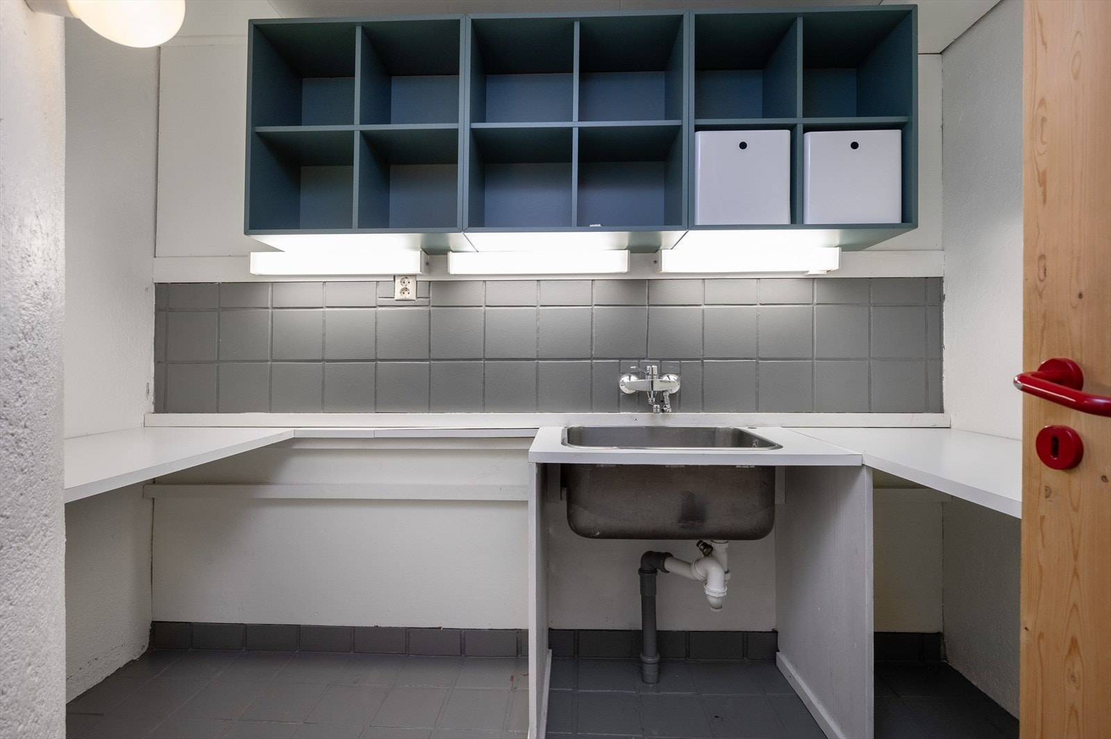 I underetasjen er det et vaskerom bestående av fliser på gulv og dels vegg. Rommet består av vaskeromsinnreding med ståkum og benkeplate. Det er montert hyller over. Galleribilde