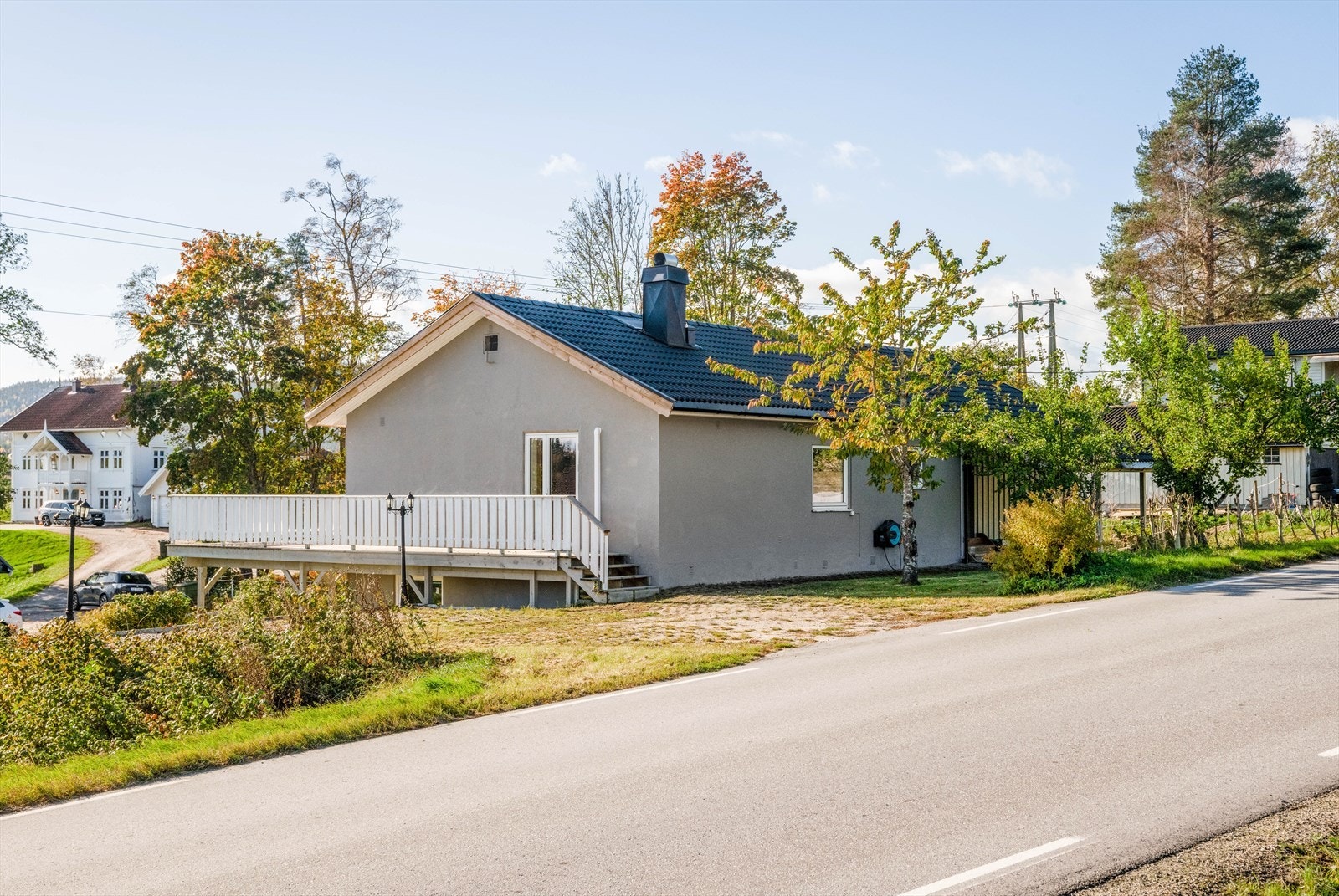 Innkjørsel og gårdsplass med belegningsstein. Gårdsplassen er terrengtilpasset, med støttemur av fabrikkfremstilte betongblokker. Galleribilde