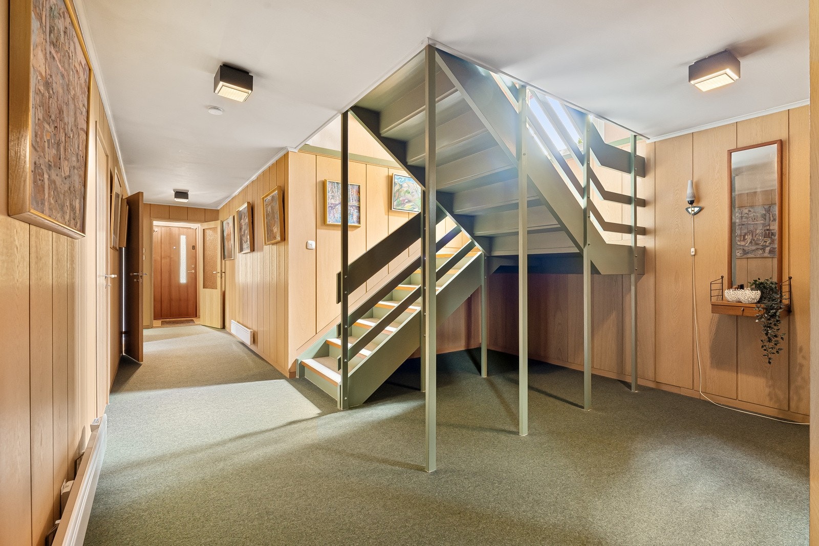 Trappeløp til hall i sokkeletasje; 3 soverom på rad, vindfang/entré i enden. Gasasjen i vinkelen midt i bildet. Galleribilde