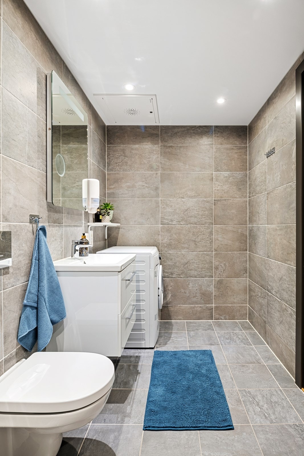 Badet er innredet med servantløsning med skap, speil med belysning og vegghengt toalett. Galleribilde