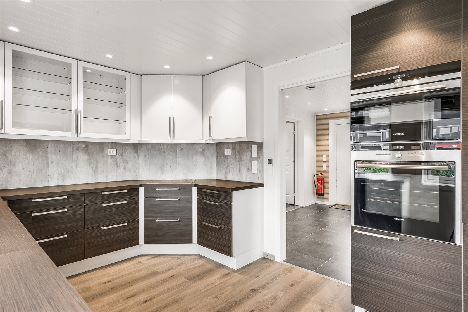 Innredning med hvite malte slette dører, noen med glass. Dører med trefront i sort farge og laminat benkeplate med underlimt vask i sort komposittmateriale. Galleribilde