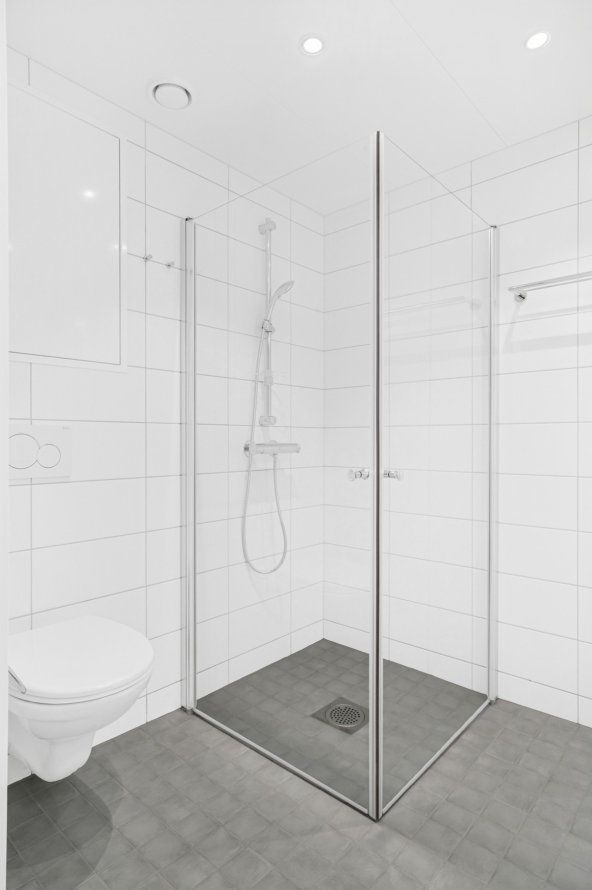Badet har kvaliteter som dusjdører i glass, vegghengt toalett og spotter i tak. Galleribilde