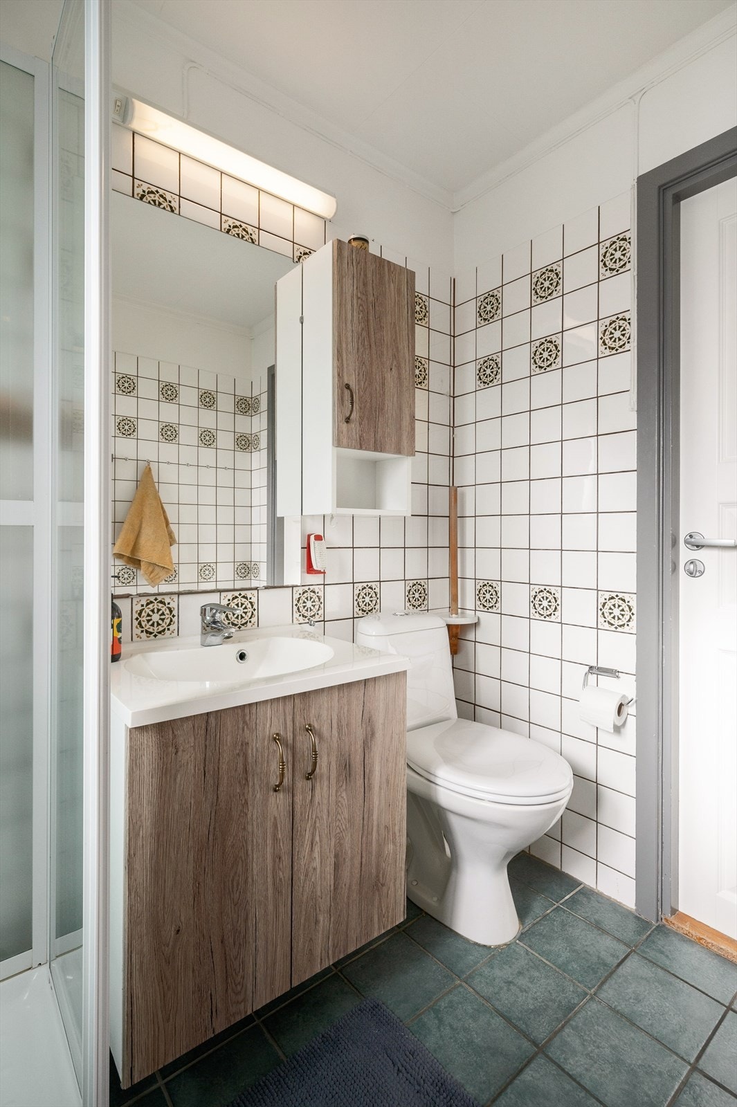 Badet er innredet med dusjkabinett, gulvmontert toalett og baderomsinnredning Galleribilde