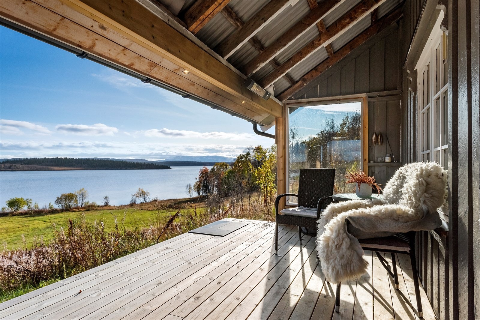 Nydelig utsikt mot Røssvatnet og Røssvassholmen fra terrassen. Delvis takoverbygd terrasse på ca. 17,5 m2. Her er det god plass for hygge på fine dager. Legg merke til de innfelte lysene under taket. Galleribilde