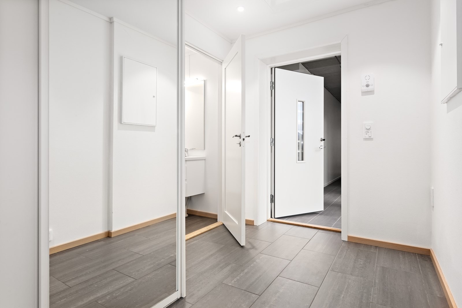 Flisbelagt inngangsparti med stor skyvedørs garderobe. Leiligheten har også et ekstra toalett med servant lokalisert ved inngangenpartiet. Galleribilde
