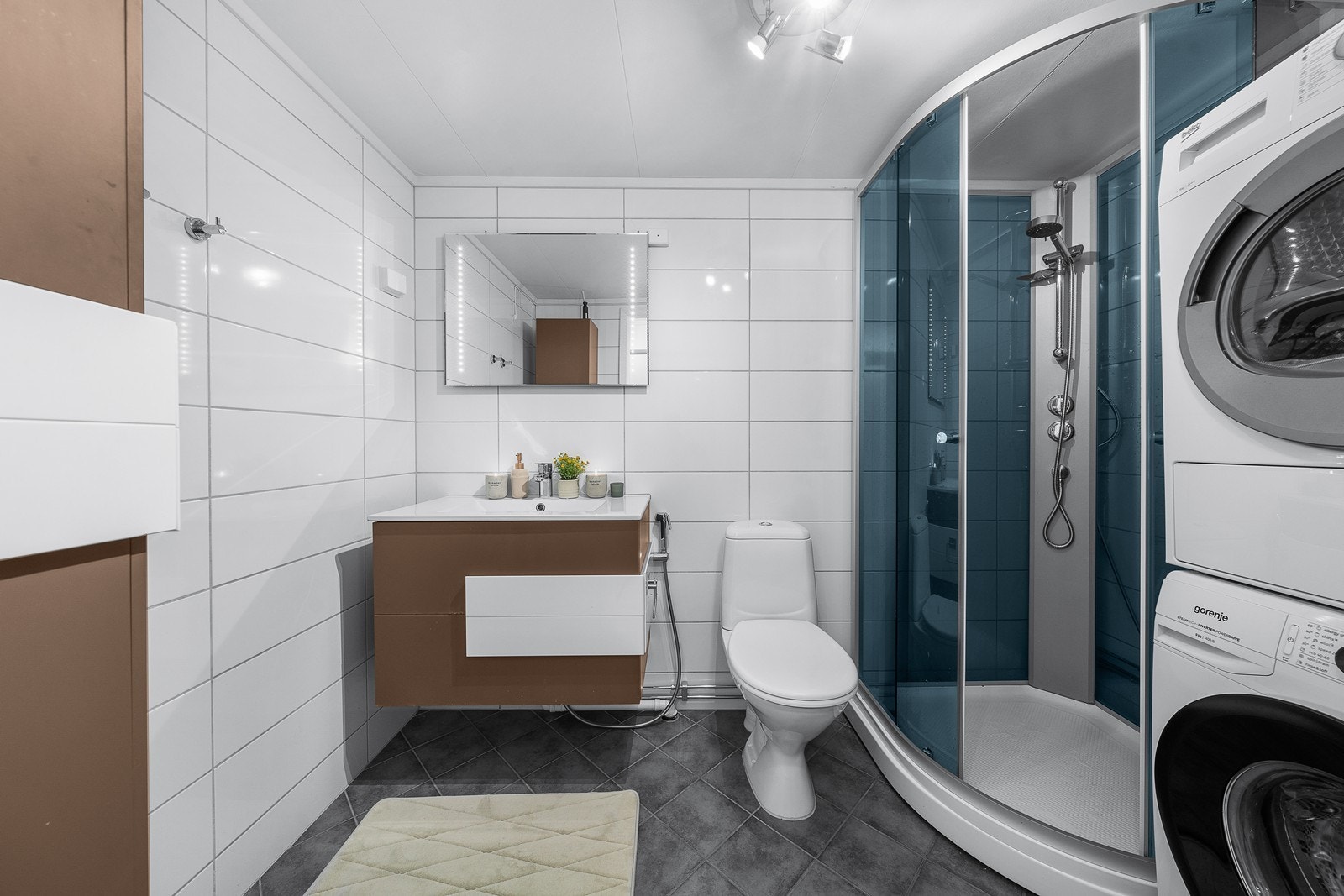 Pent flislagt bad oppusset i 2011. Badet er utstyrt med dusjkabinett montert i 2021, gulvstående wc med sidemontert hånddusj, servantinnredning med skuffer, samt opplegg og plass til både vaskemaskin og tørketrommel. Galleribilde